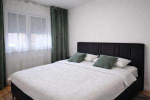 a bedroom with a large bed with two green pillows at Hari Apartmani Oaza in Tuzla