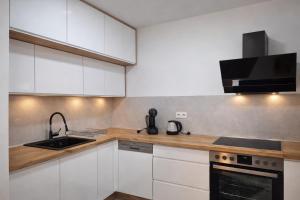a kitchen with white cabinets and a sink and a stove at Hari Apartmani Oaza in Tuzla