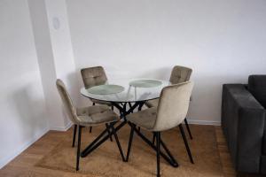 a dining room with a glass table and four chairs at Hari Apartmani Oaza in Tuzla +3 photos
