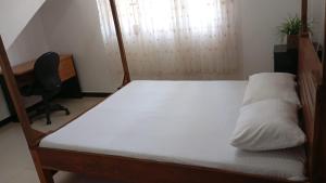a bedroom with a bed with white sheets and a desk at Bright Nest Villa in Matara