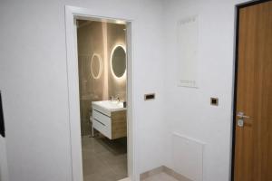 a white bathroom with a sink and a mirror at Muki Park Lake in Tuzla