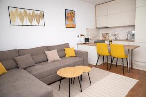a living room with a couch and a table and yellow chairs at Muki Park Lake in Tuzla