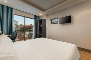 a bedroom with a white bed and a large window at Aurora Hotel & Apartment in Hanoi