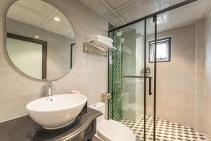 a bathroom with a sink and a mirror and a shower at Aurora Hotel & Apartment in Hanoi