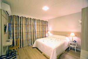 a bedroom with a bed and a table with two lamps at Moinho Itália Hotel in Campos do Jordão