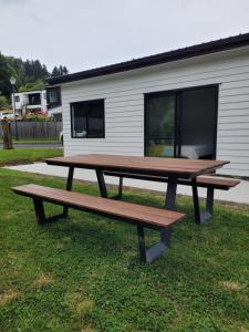 two picnic tables sitting in the grass in front of a house at Clearwater Private Guest Suite in Dunedin