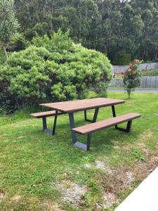 a wooden picnic table sitting in the grass at Clearwater Private Guest Suite in Dunedin