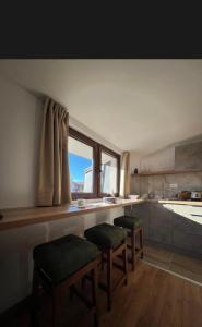 a kitchen with two stools and a counter with a window at Apartments SKY Kopaonik in Kopaonik