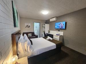 a bedroom with a bed and a tv on a wall at Crest Motor Inn in Queanbeyan