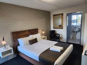 a bedroom with a large bed and a bathroom at Crest Motor Inn in Queanbeyan