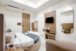 a bedroom with a bed and a mirror and a couch at Hotel Lee Paramount in Gandhinagar