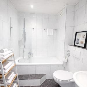 a white bathroom with a tub and a toilet at Penthouse mit Deisterblick & Balkon in Barsinghausen +8 photos