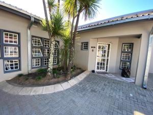 a house with palm trees in front of it at Dukes Chambers in Harrismith