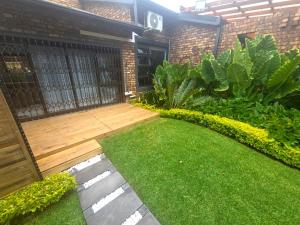 a garden with a wooden deck and green grass at Indulge Deluxe Accommodation in Middelburg