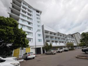 a large white building with cars parked in a parking lot at TJ Homes in Ross Island