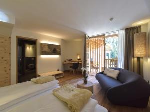 1 dormitorio con cama, sofá y sala de estar en Hotel Vajolet, en San Cassiano