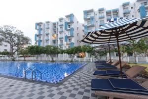a row of chairs and an umbrella next to a swimming pool at Santorini Negombo in Negombo