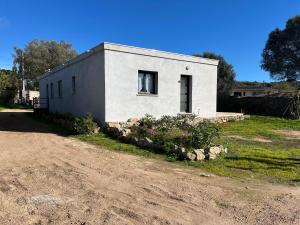 a small white building on the side of a dirt road at La Détente in Bonifacio