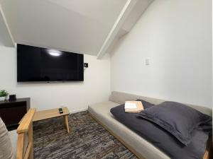 a bedroom with a bed and a flat screen tv at 宿andFanハマハマ in Meinohama