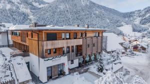 a house in the snow with mountains in the background at Mölgg Dolomites Residence in San Vigilio Di Marebbe