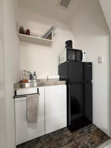 a small kitchen with a black refrigerator and a sink at 宿andFanハマハマ in Meinohama