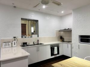 a white kitchen with a sink and a stove at Saltbush Cottage in Broken Hill