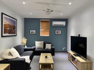 a living room with a couch and a tv at Saltbush Cottage in Broken Hill