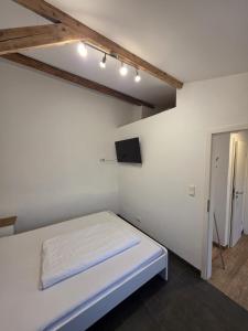 a white room with a bed and a tv at Maimühle Appartements in Perl