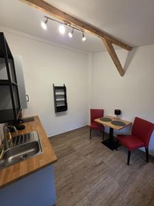 a kitchen with a sink and a table with red chairs at Maimühle Appartements in Perl