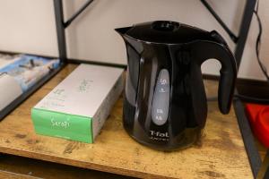 HanazonomachiにあるROOMzero 1号室の本の横のテーブルの上に置かれた紅茶のやかん