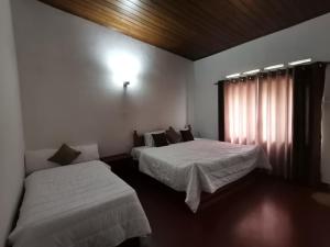 a hotel room with two beds and a window at Felix Holiday Bungalow in Ella