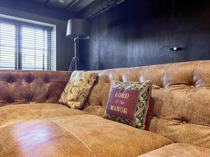 a brown leather couch with a pillow on it at Oaklands Farm - Cottage 5 in Broughton +6 photos