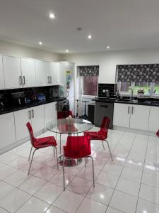 a kitchen with a glass table and red chairs at North Birmingham in Holly Lane