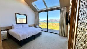 a bedroom with a bed and a large window at Guide Hill Station Lodge in Lake Tekapo