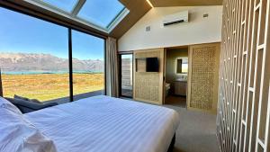 a bedroom with a bed and a large window at Guide Hill Station Lodge in Lake Tekapo