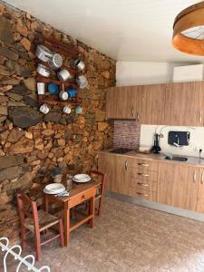 a kitchen with a table and a stone wall at Monte Vilão in Soudes