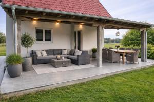 a covered patio with a couch and a table at Holiday Home Kostandinovic in Modriča