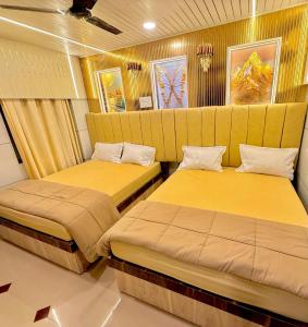 two beds in a room with yellow walls at Hotel rajmahel chotila in Chotila