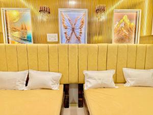 two beds in a room with paintings on the wall at Hotel rajmahel chotila in Chotila