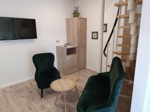 a living room with two green chairs and a tv at Kastanienhof Lübben in Lübben