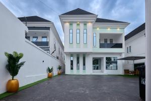 a white house with a courtyard in front of it at Buddy's Court Luxury 5Bedroom,3 & 2bed Apartment in Ikeja