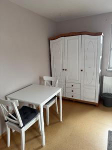 a white table and a chair and a cabinet at Ferienwohnung Schürer in Lauter