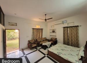 a bedroom with a bed and a couch and a window at Shree Govindam kunj Villa in Jaipur
