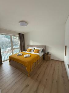 a bedroom with a bed with yellow sheets and a large window at ApartmanBrezovina217 in Veselé