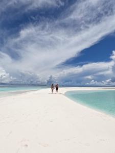two people walking on a white beach with the ocean at Island Scuba in Dhangethi +34 photos