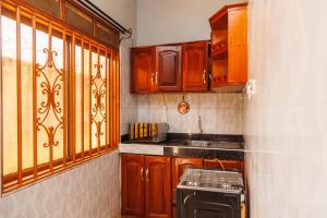a small kitchen with wooden cabinets and a stove at Palm Haven Furnished Apartments in Bweyogerere
