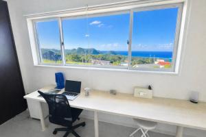 a desk with a laptop and a window at Saraswati in Nakijin