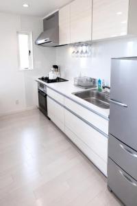a white kitchen with a sink and a refrigerator at Saraswati in Nakijin