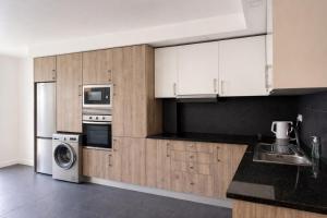 a kitchen with white cabinets and a washer and dryer at Zena Park - Near Lisbon in Odivelas