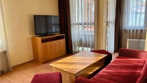 a living room with a tv and two red chairs at Hotel Veronika Devin in Devin